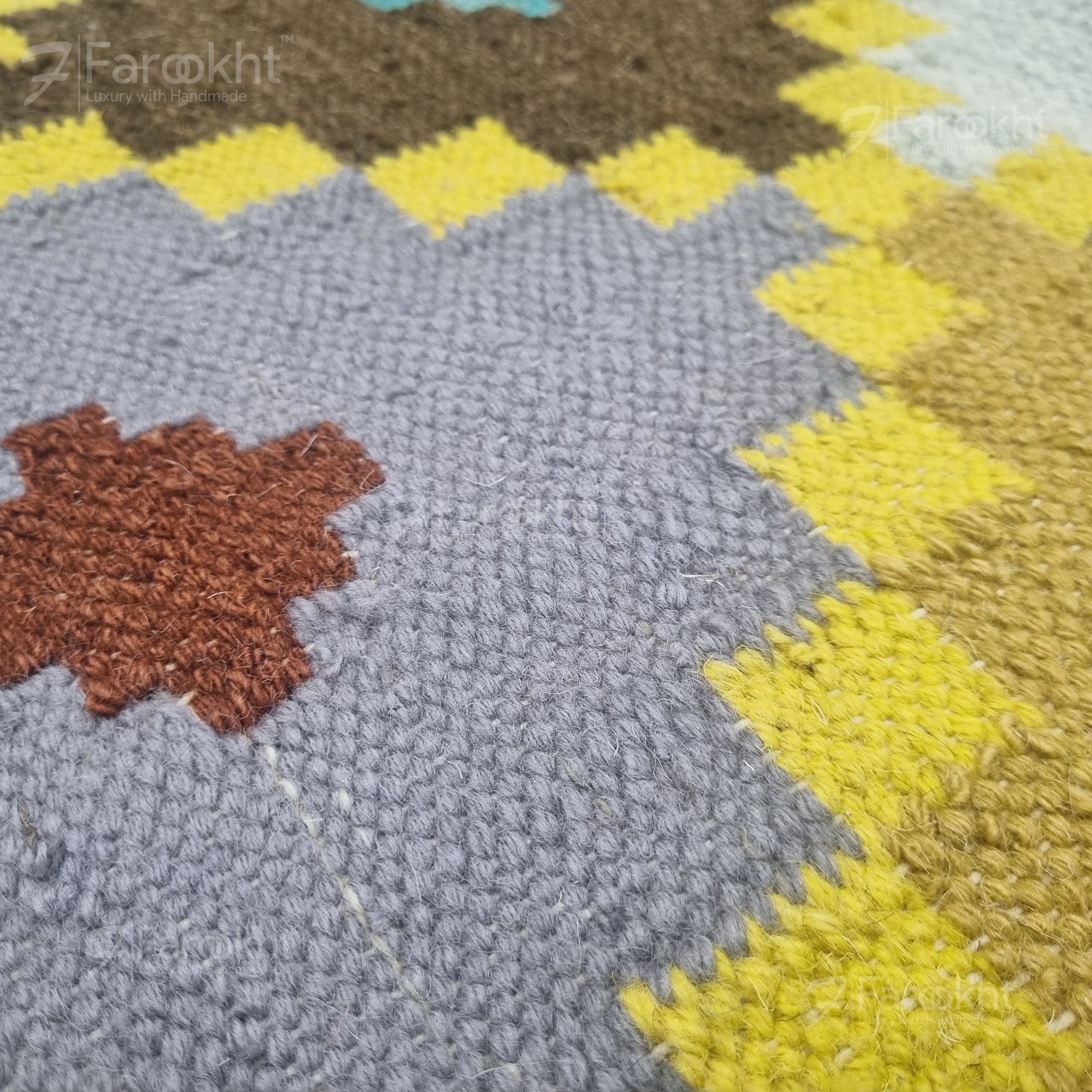 Close-up of a textured rug with geometric pattern featuring brown, gray, and yellow colors.