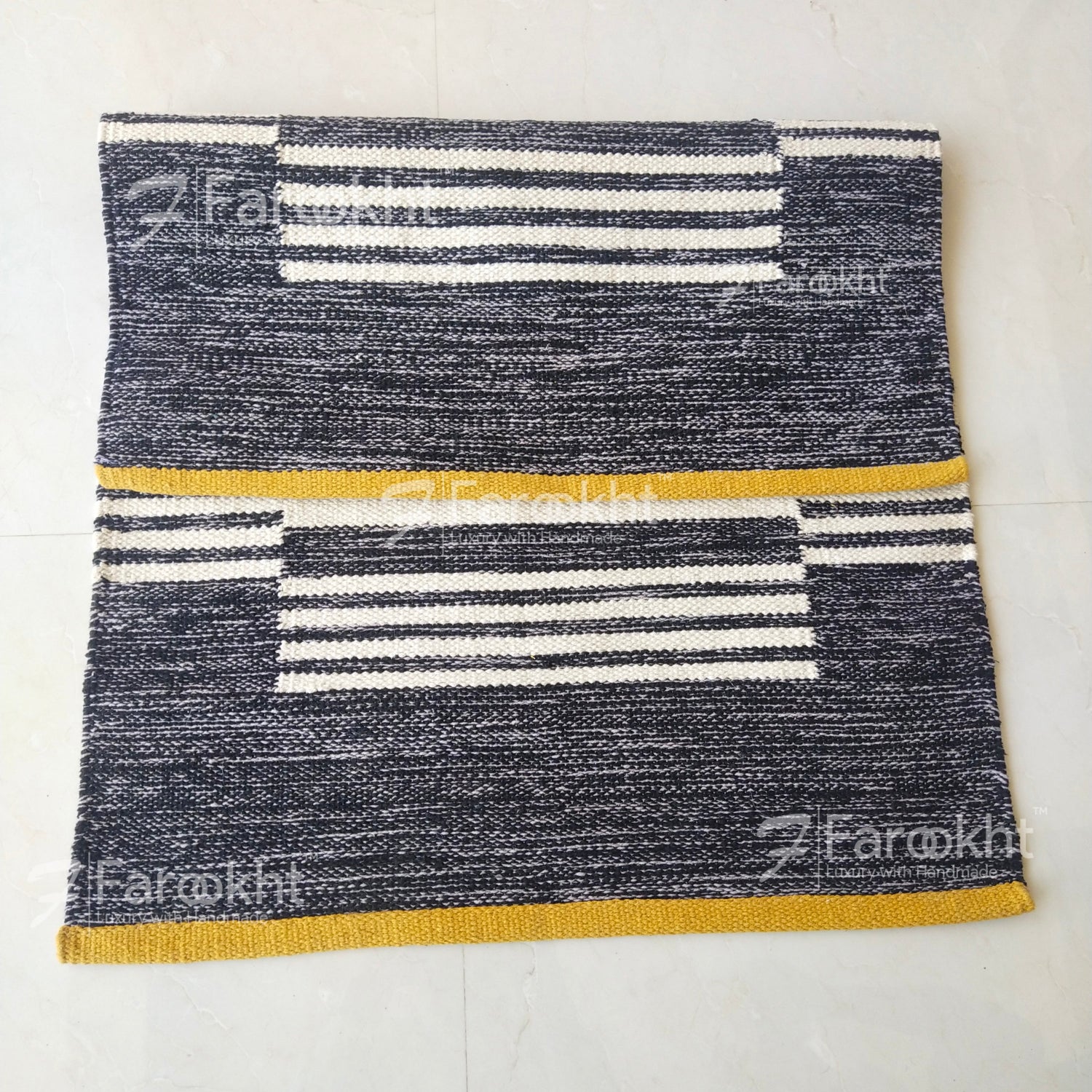 Textured rug with striped pattern on a white floor, featuring the brand &