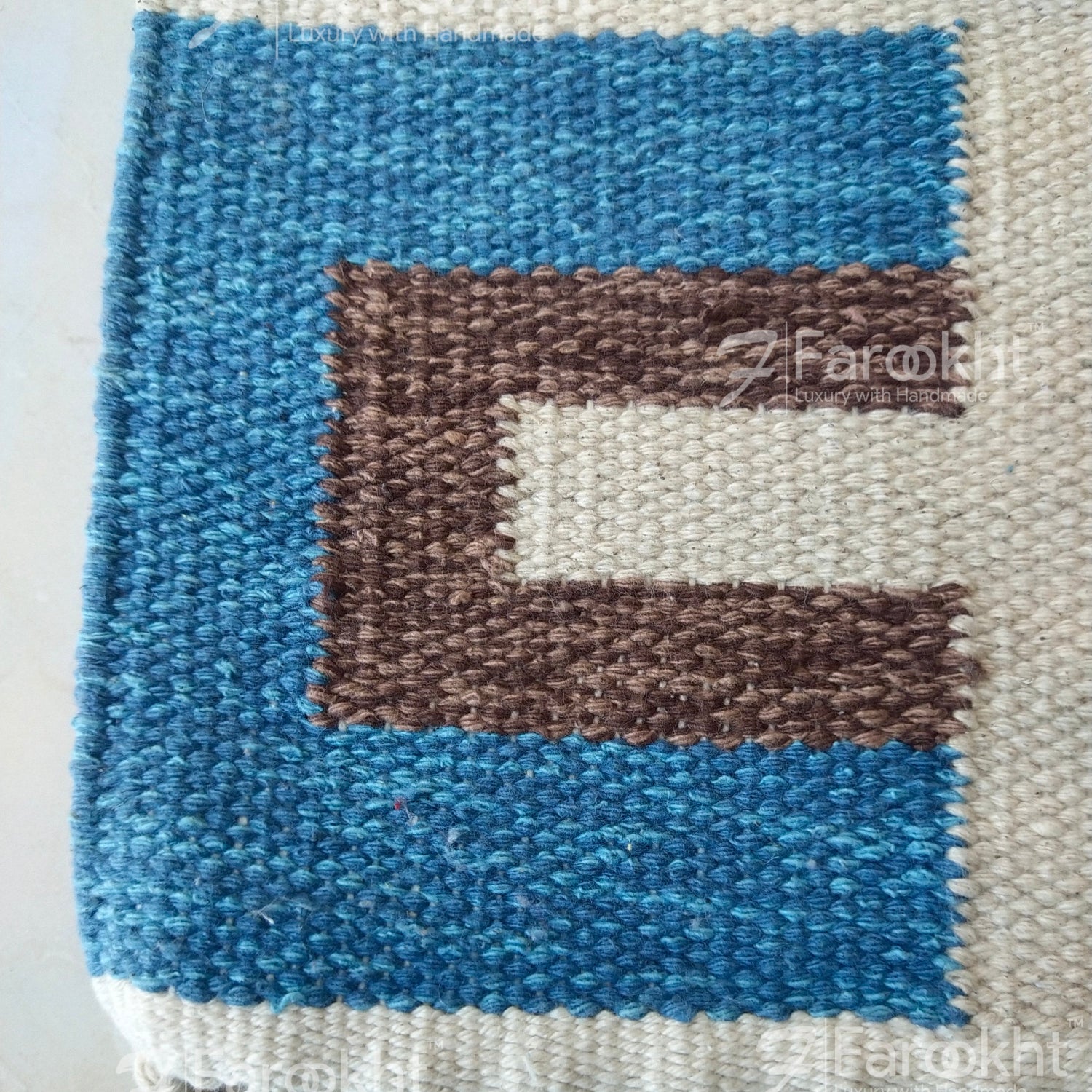 Textile art piece with blue, brown, and white pattern on a plain background