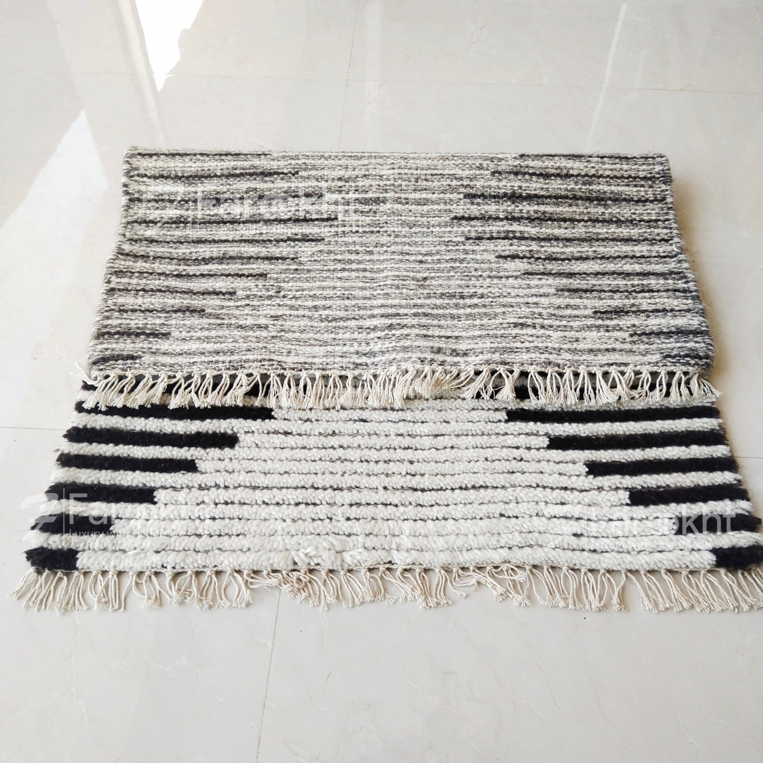 Black and white striped rug with fringes on a light gray floor.