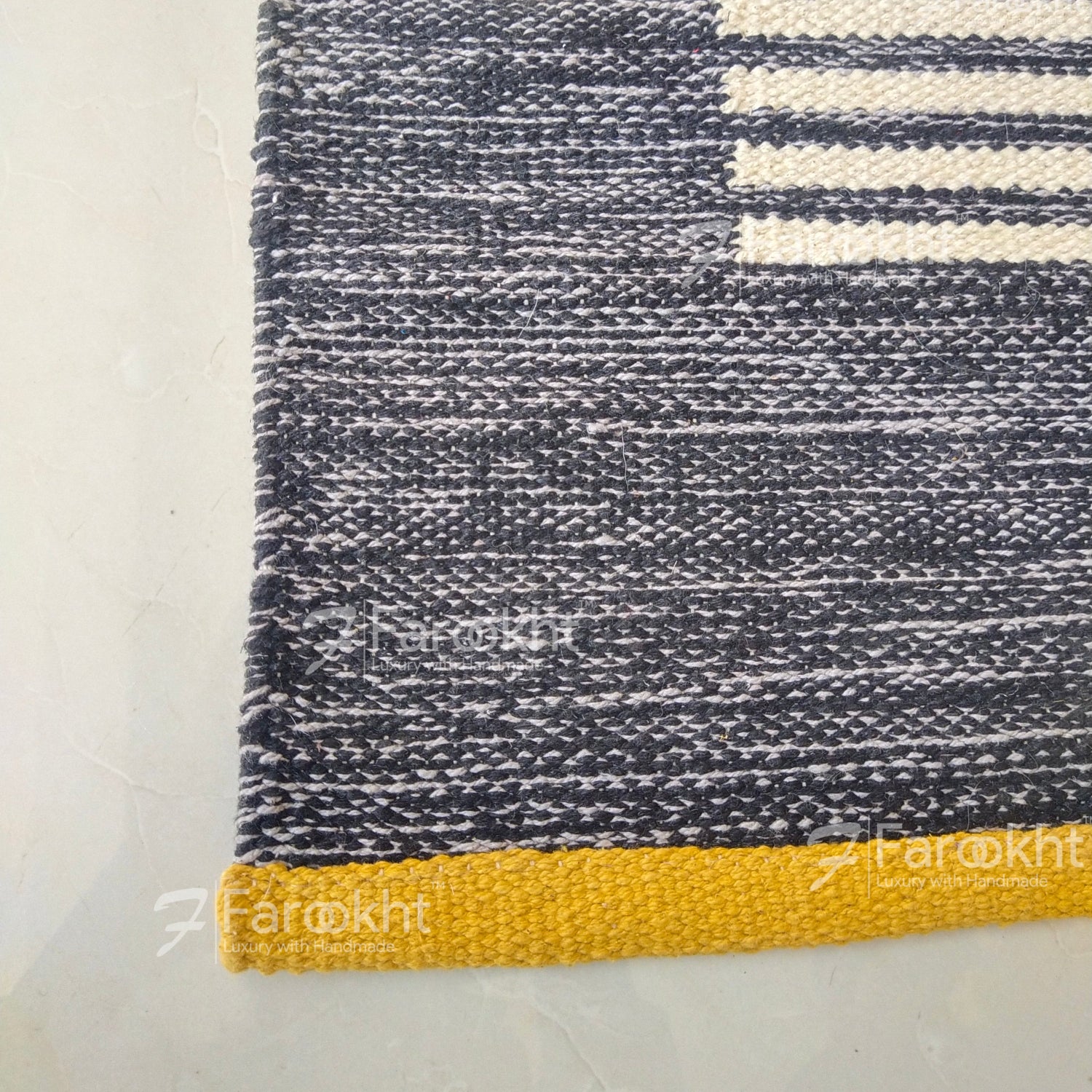 Textured blue and white rug with a yellow border on a light gray floor.