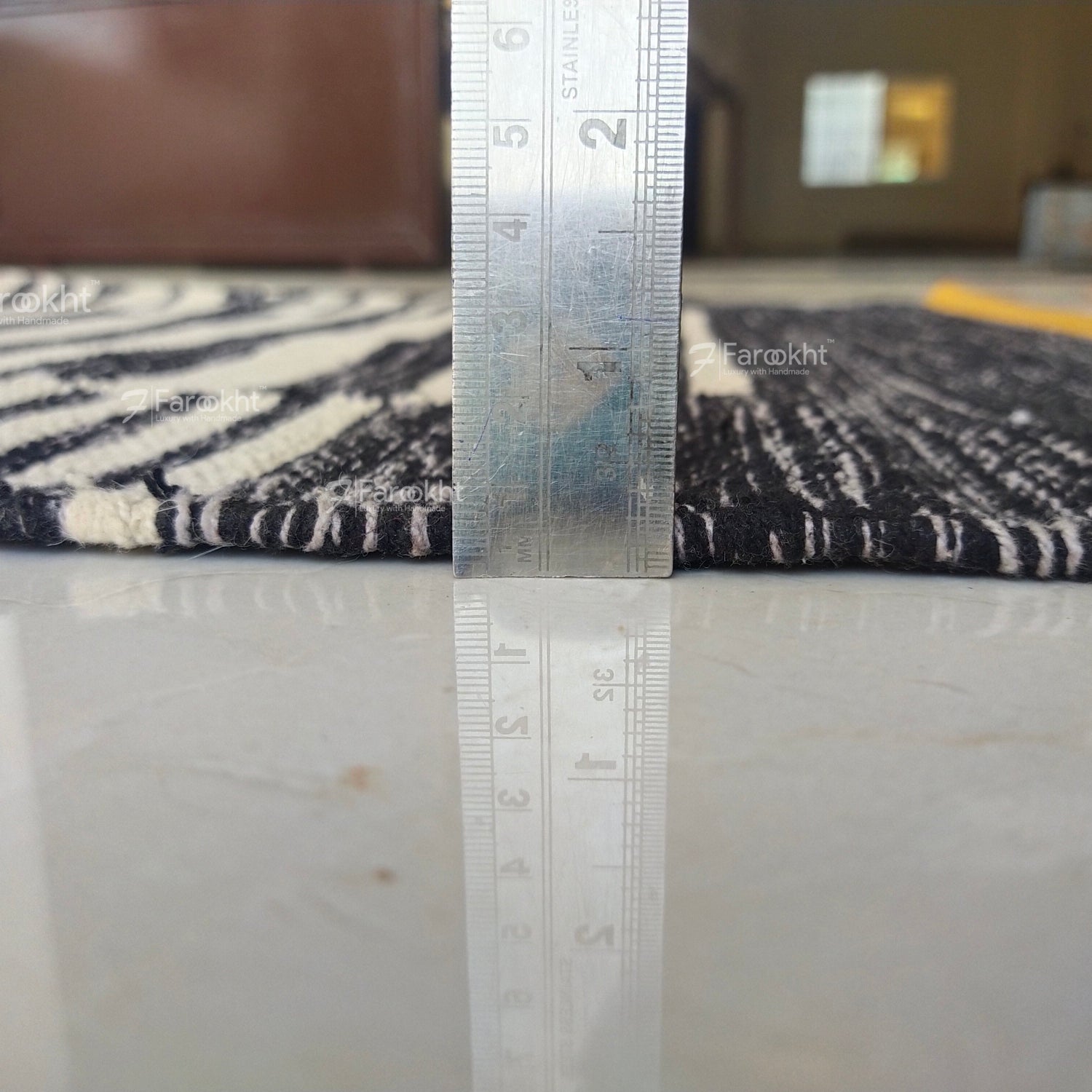 Rug with a ruler showing measurements on a marble floor.