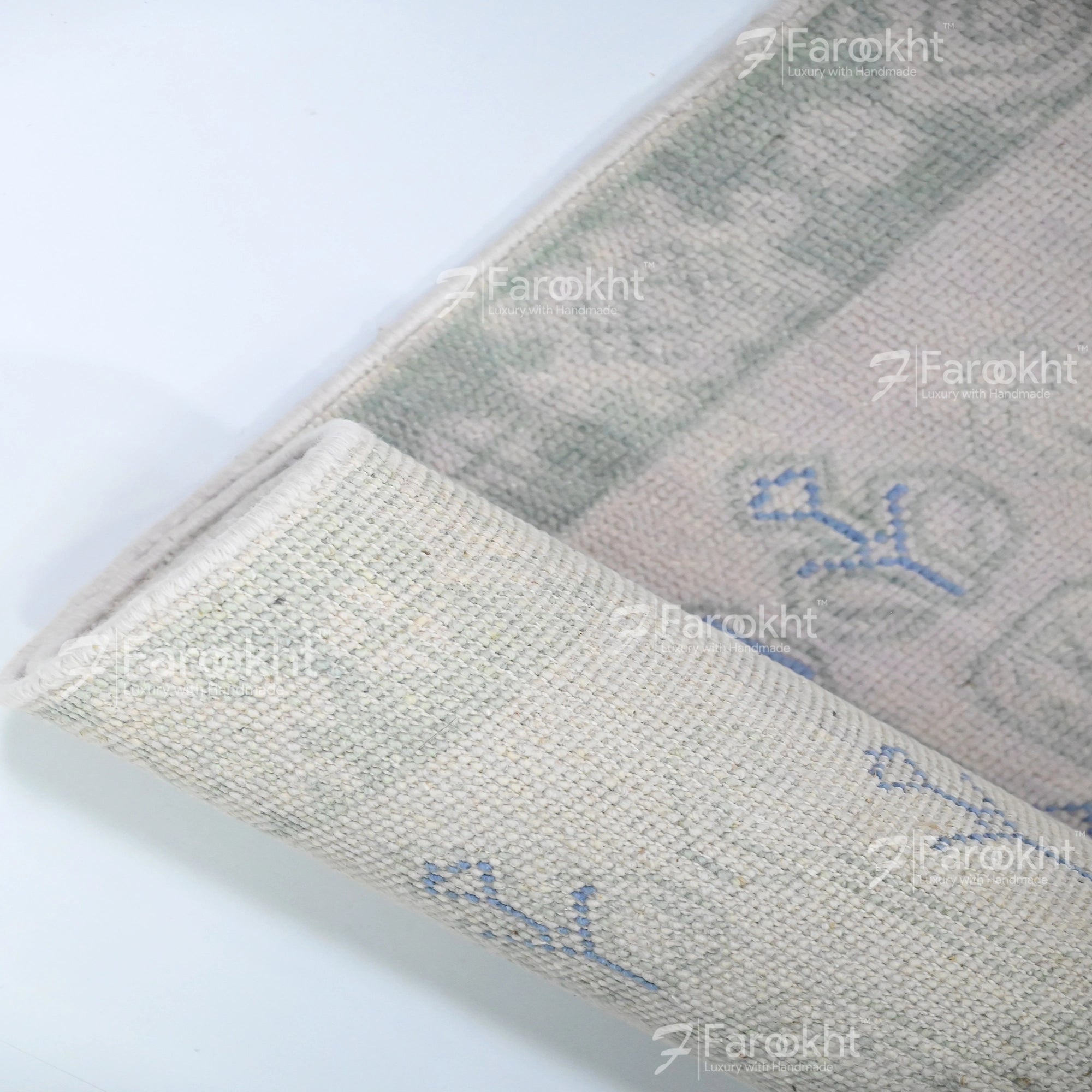 Close-up of a textured fabric with embroidered designs on a white background, featuring the brand &