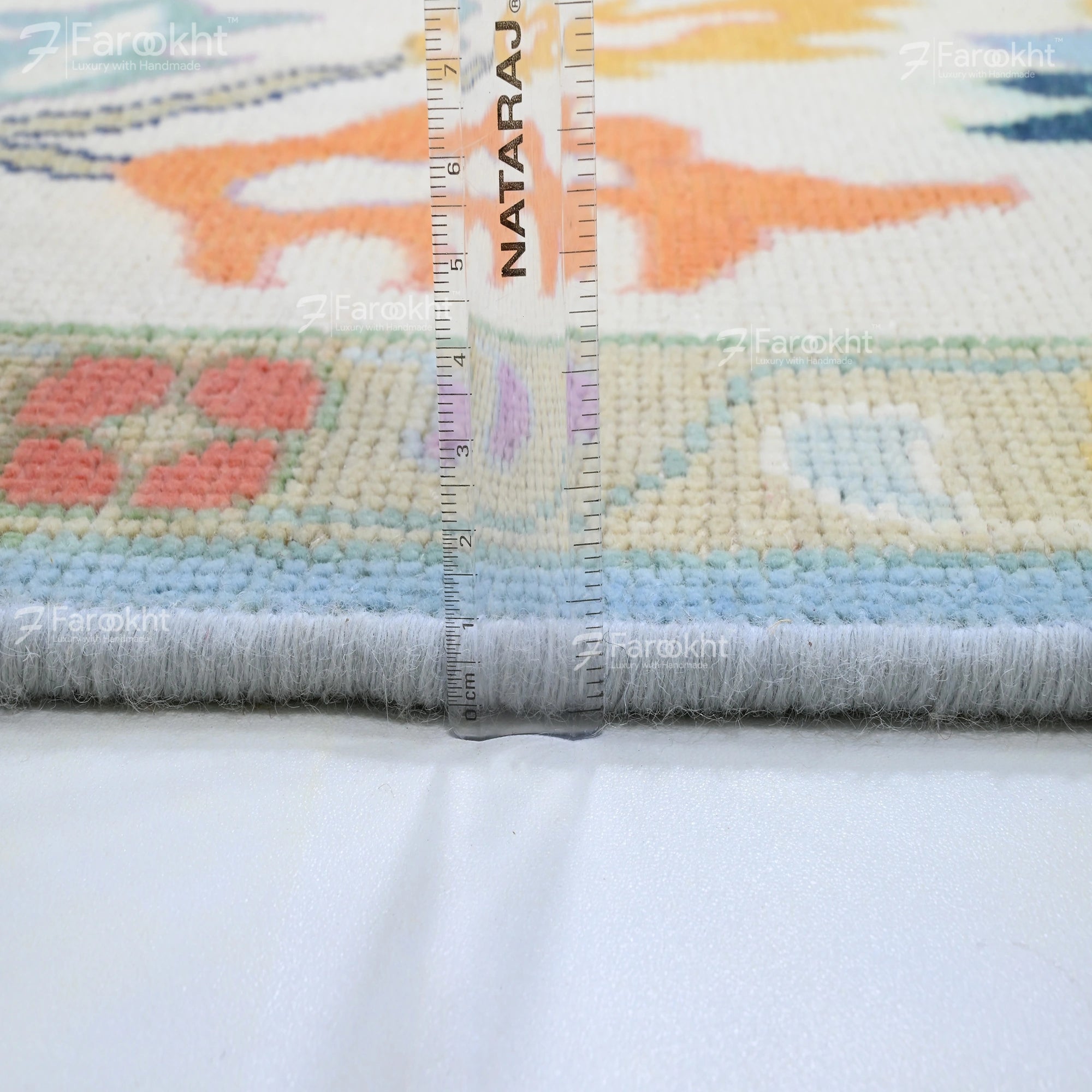 Colorful rug with a ruler for scale, featuring the brand &