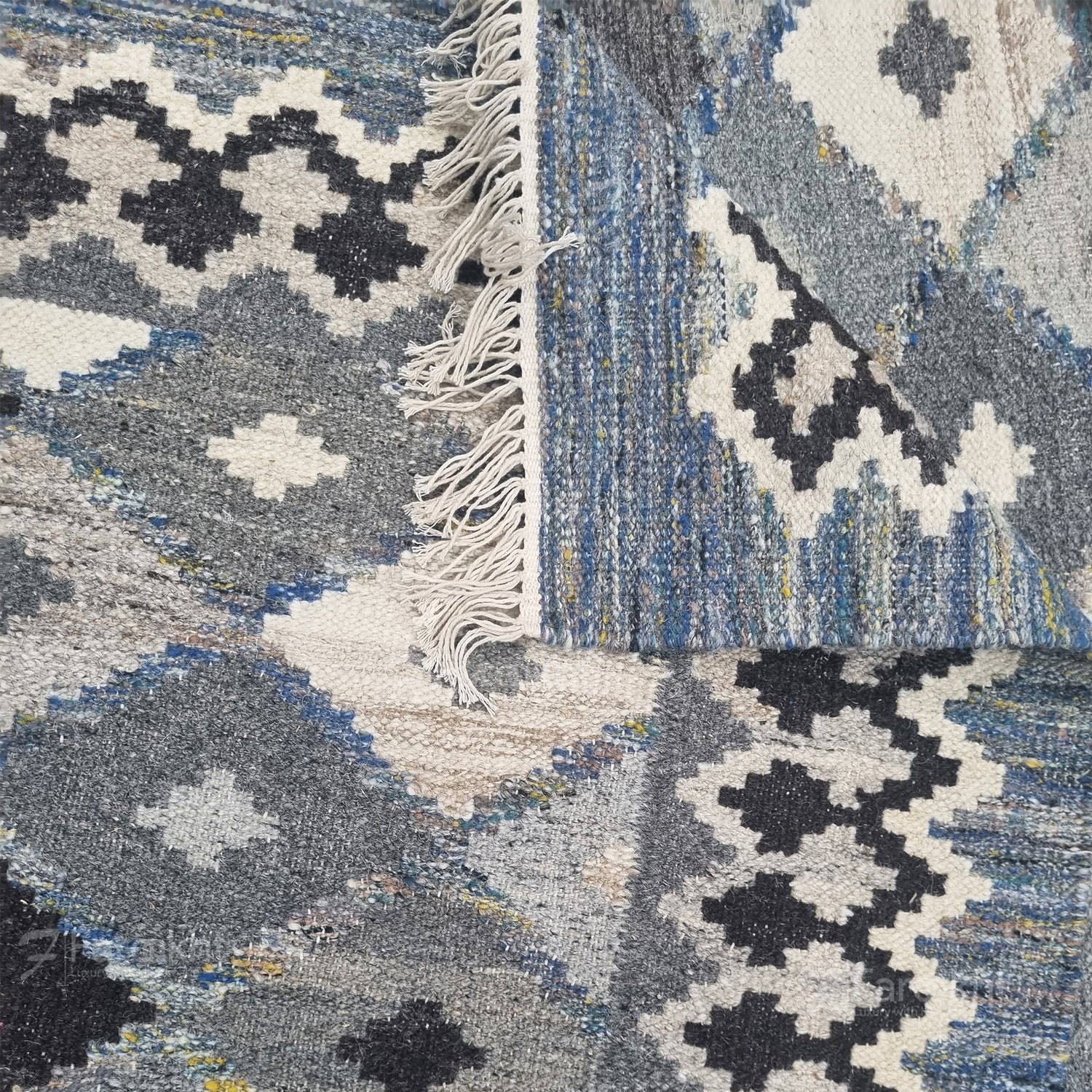Close-up of a patterned rug with geometric designs in blue, gray, and white.