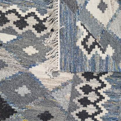 Close-up of a patterned rug with geometric designs in blue, gray, and white.
