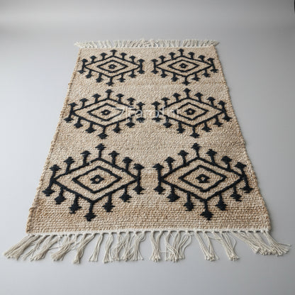 Woven rug with black geometric patterns and white fringe on a light background