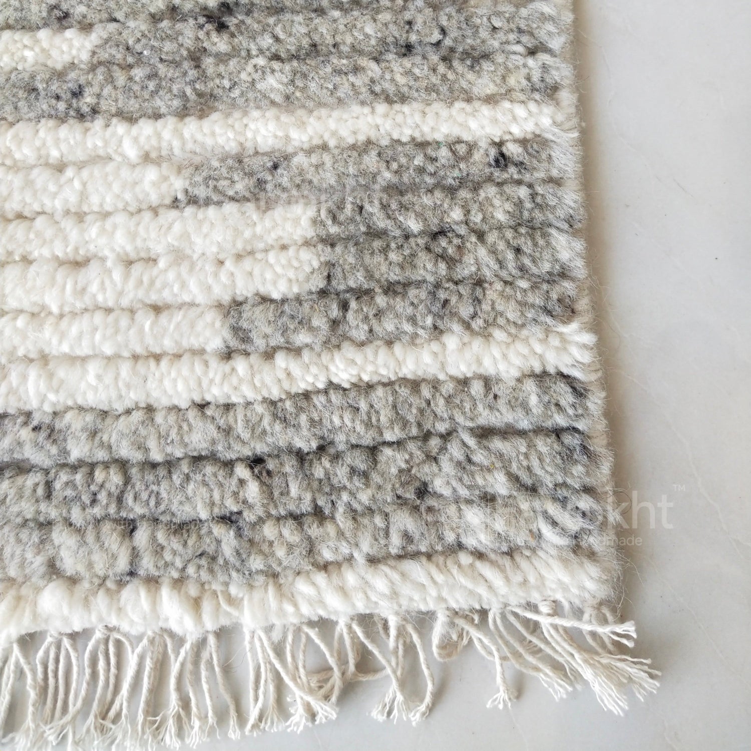 Textured rug with white and gray stripes on a light background
