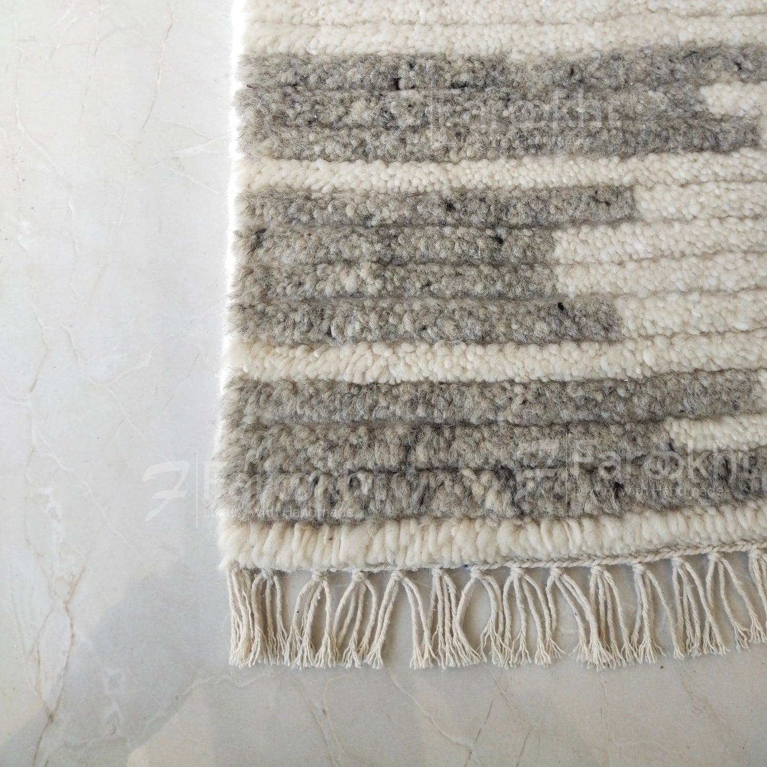 Textured area rug with striped pattern and tassels on a light background