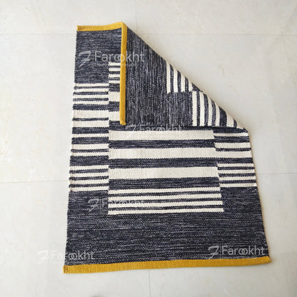 Textured rug with geometric pattern on a white floor, branded &