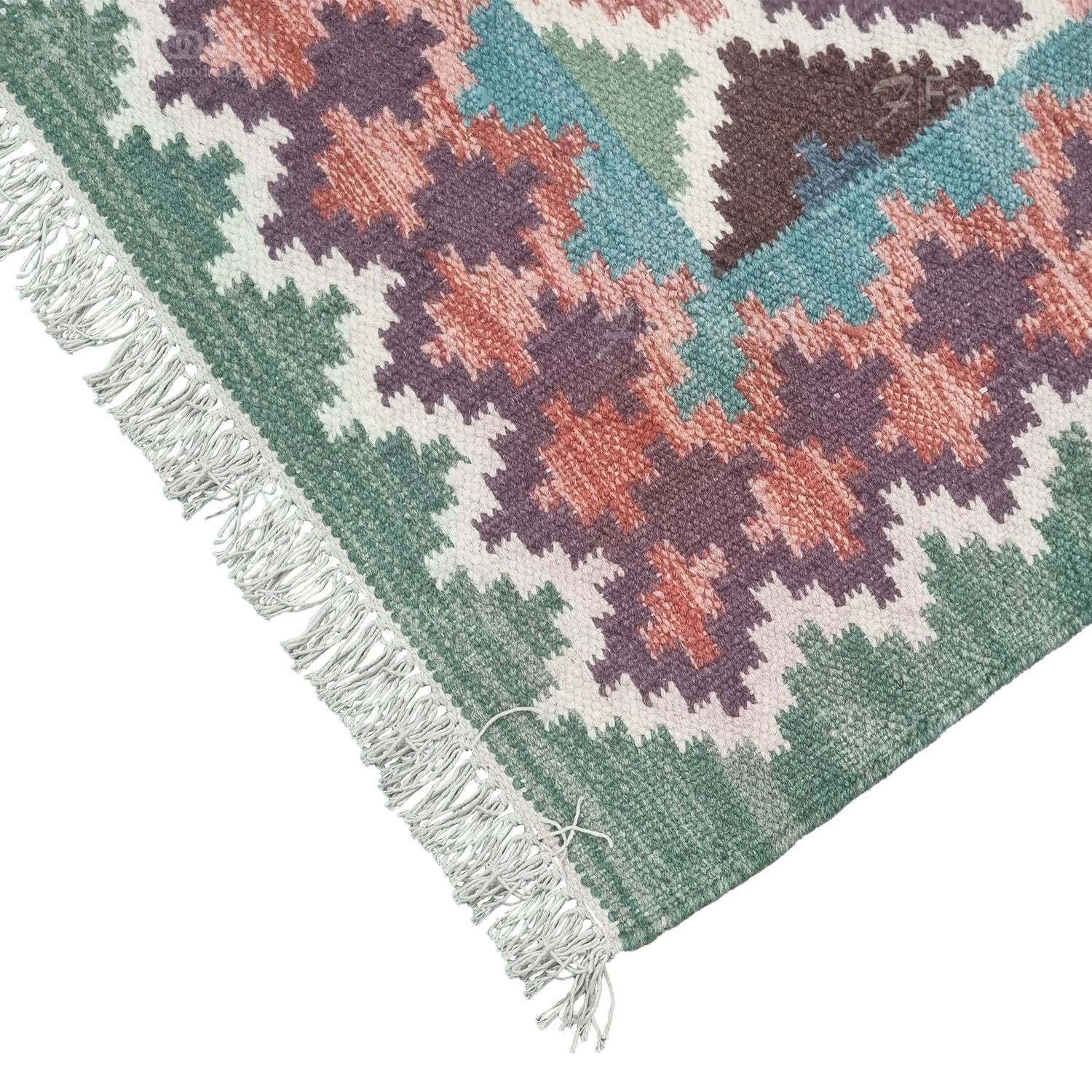 Close-up of a colorful geometric-patterned rug with fringes on a white background