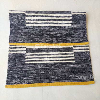 Textured rug with striped pattern on a white floor, featuring the brand &