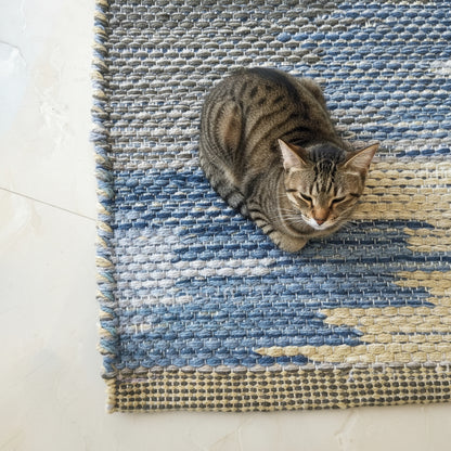 Close-up of a blue and beige patterned rug on a light-colored floor.