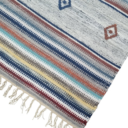 Woven textile with colorful stripes and fringe on a white background