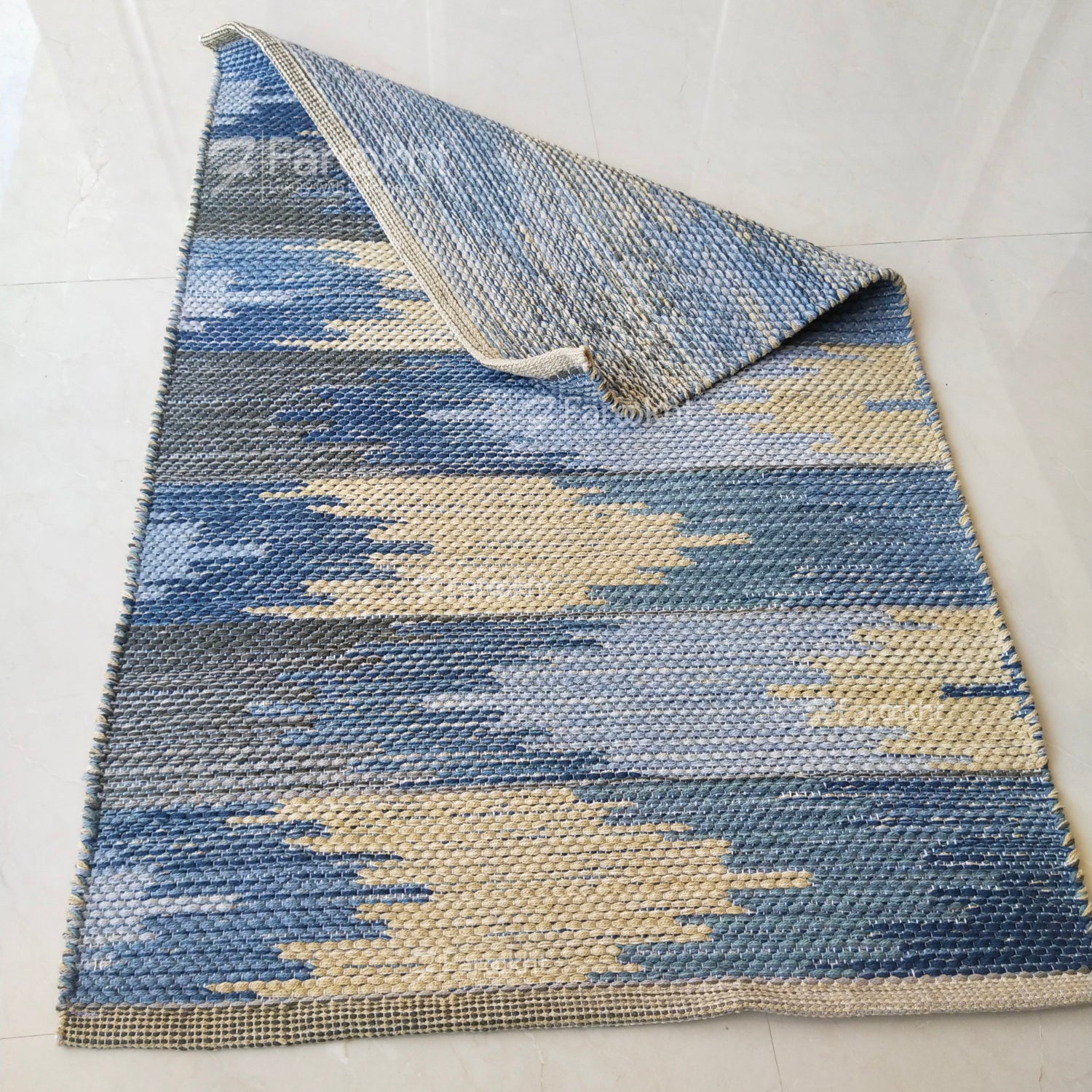 Blue and beige patterned rug on a white floor