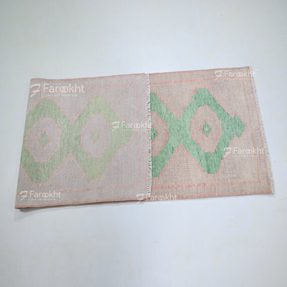 Woven mat with green geometric pattern on a white background, branded &
