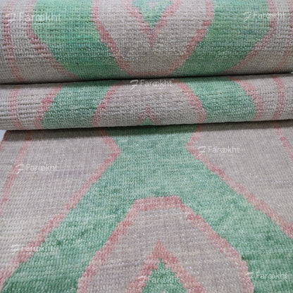Close-up of a textured fabric with green and pink geometric pattern