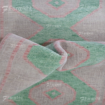 Close-up of a patterned fabric with geometric design, featuring green and red colors.