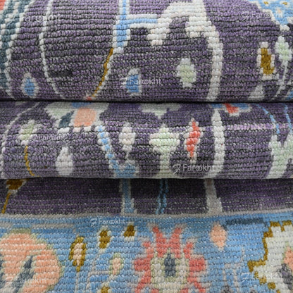 Stack of patterned rugs with floral designs on a blue and purple background.