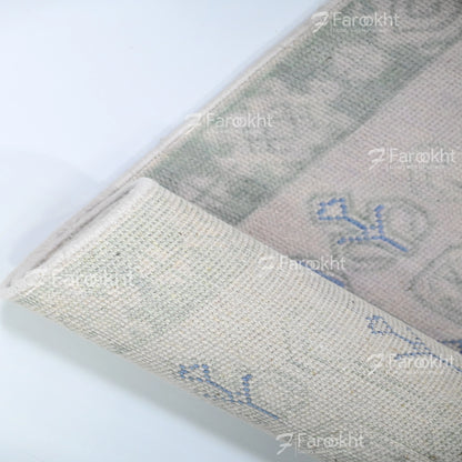 Close-up of a textured fabric with embroidered designs on a white background, featuring the brand &