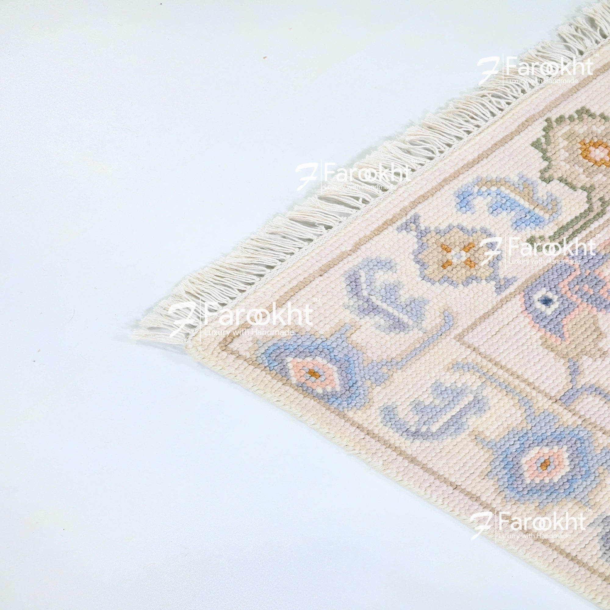Decorative rug with floral patterns and fringe on a light blue background, branded &