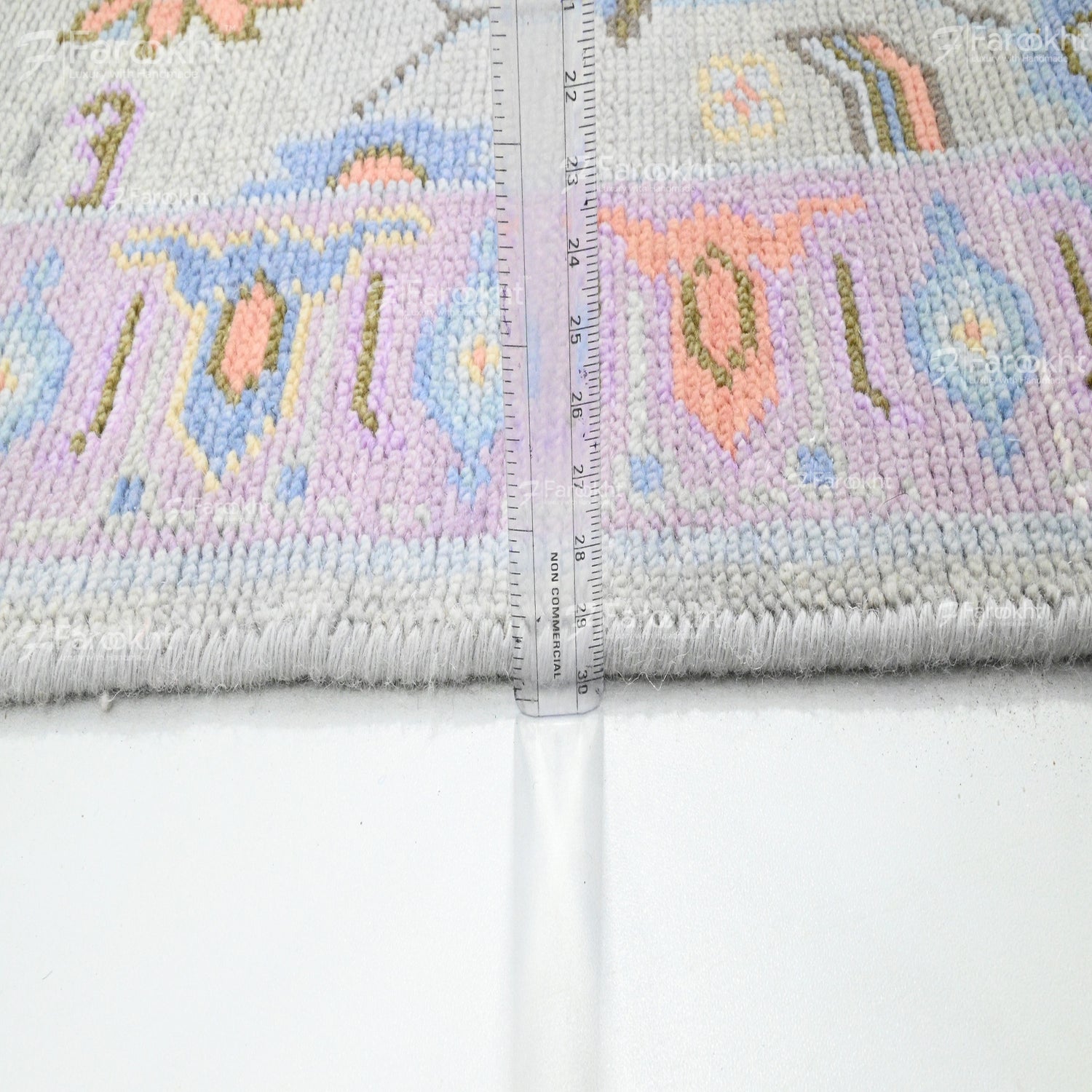 Cross-stitched fabric with colorful designs and a ruler for scale on a white background