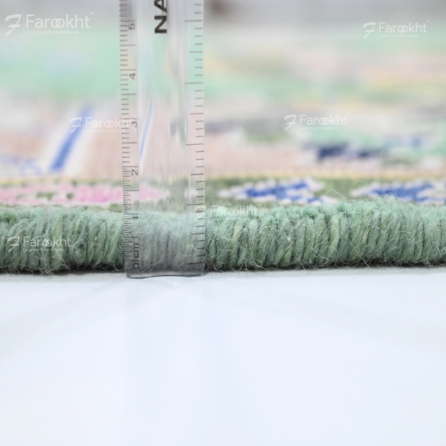 Close-up of a green carpet with a ruler for scale on a blurred background