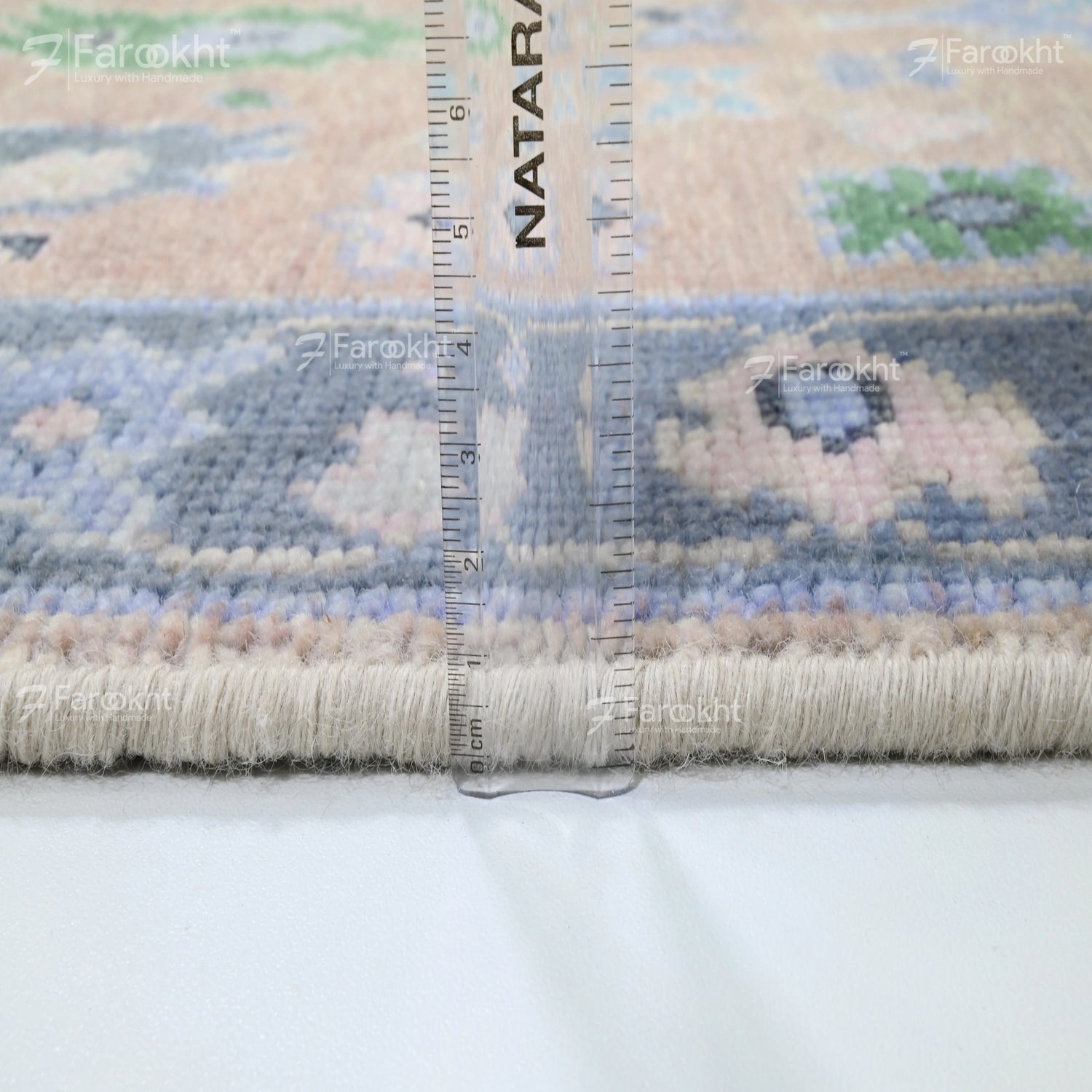 Rug with a ruler for scale on a white background, featuring the brand &